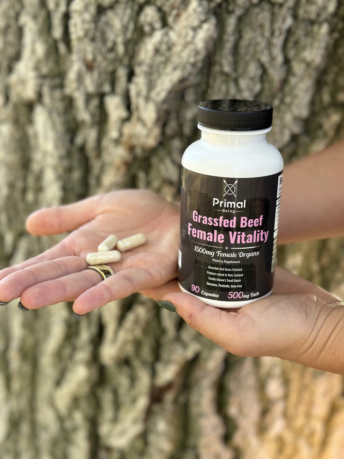 Female Vitality capsules in a hand next to the bottle